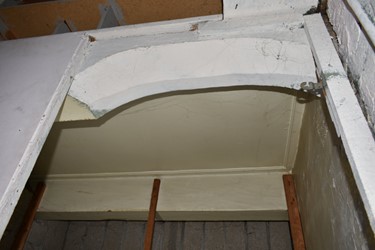 <p>Boogvormige doorgang in een zolderbalklaag grenzend aan het huidige trapgat. De boog is aan één zijde afgeschuind en verwijst daarmee naar de looprichting van de trap.</p>
